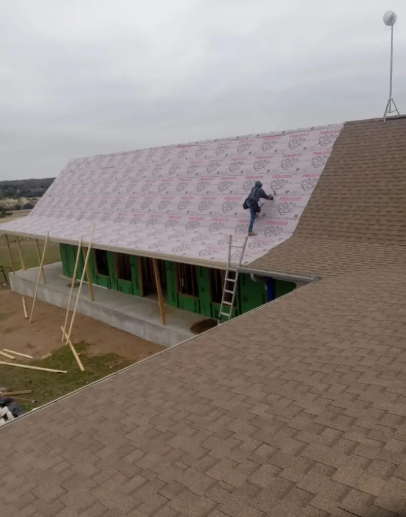 Worker preparing underlayment for a metal roof installation in Merrimac